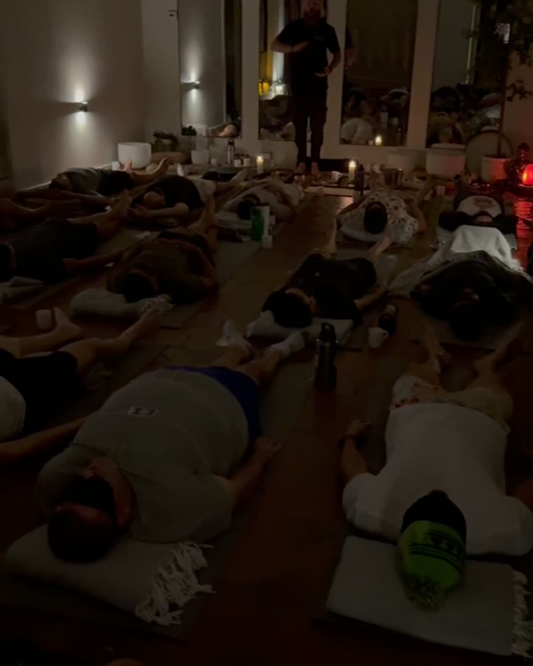 Men lying on mats during a candlelit breath session
